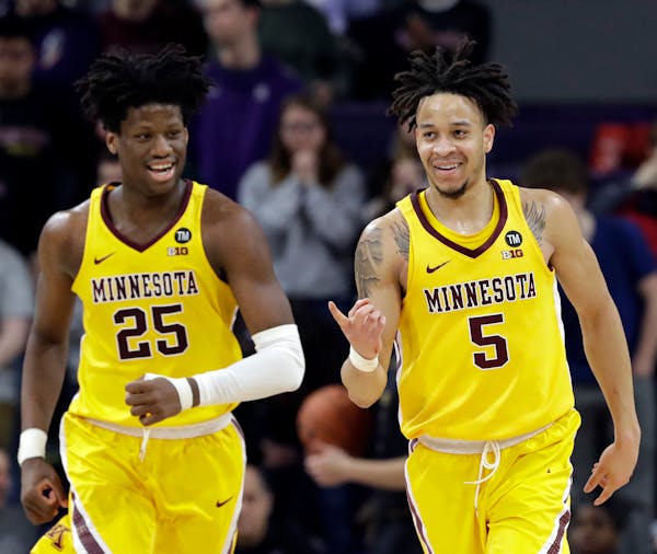Gophers guard Amir Coffey, right, smiles after scoring a basket as he runs with center Daniel Oturu during the second half