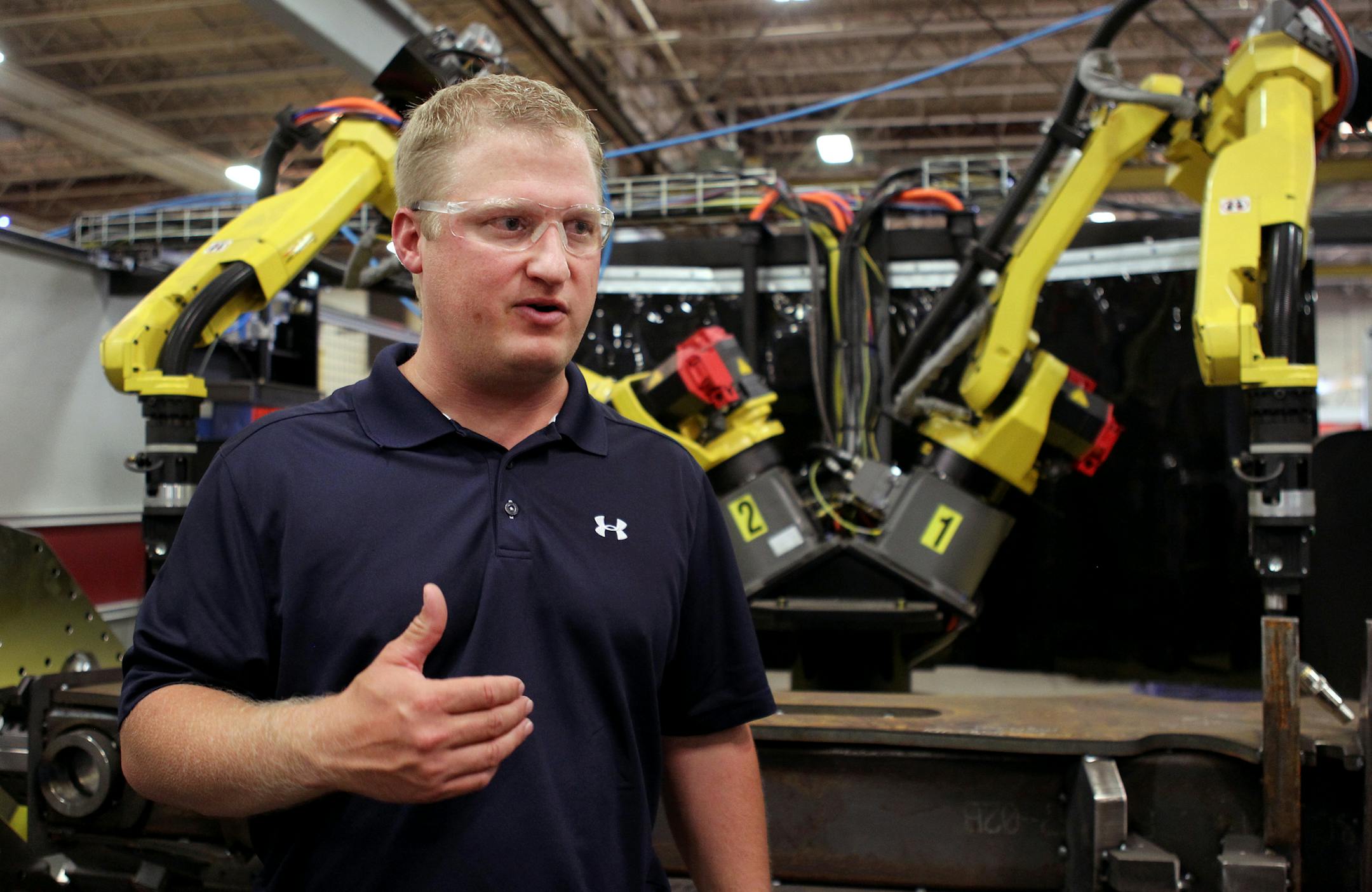 Scott Berglund, senior project manager of AGCO Jackson operations, discusses some of the new equipment, like the dual armed welding robot behind him at the AGCO North American tractor production site in Jackson, Minn., on Thursday, July 18, 2013. AGCO has implemented an expansion project to add robotic welding equipment and more workers to grow production for increasing demand. ] (ANNA REED/STAR TRIBUNE) anna.reed@startribune.com (cq)
