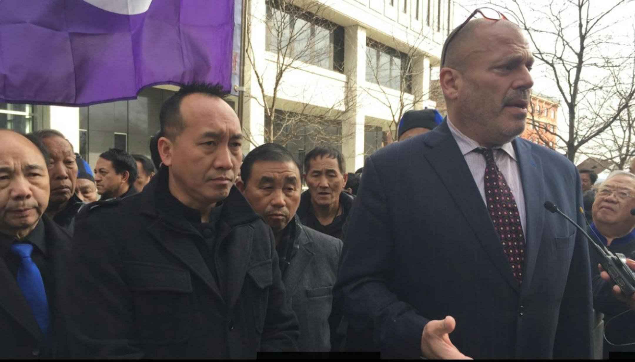 Dao Moua, left, and his attorney, Paul Applebaum, discuss a class-action lawsuit Monday afternoon outside of the federal courthouse in downtown St. Paul. Several dozen people rally behind them demanding their money back, but also supporting the man convicted of duping them out of $1.2 million. (Photo by Chao Xiong)