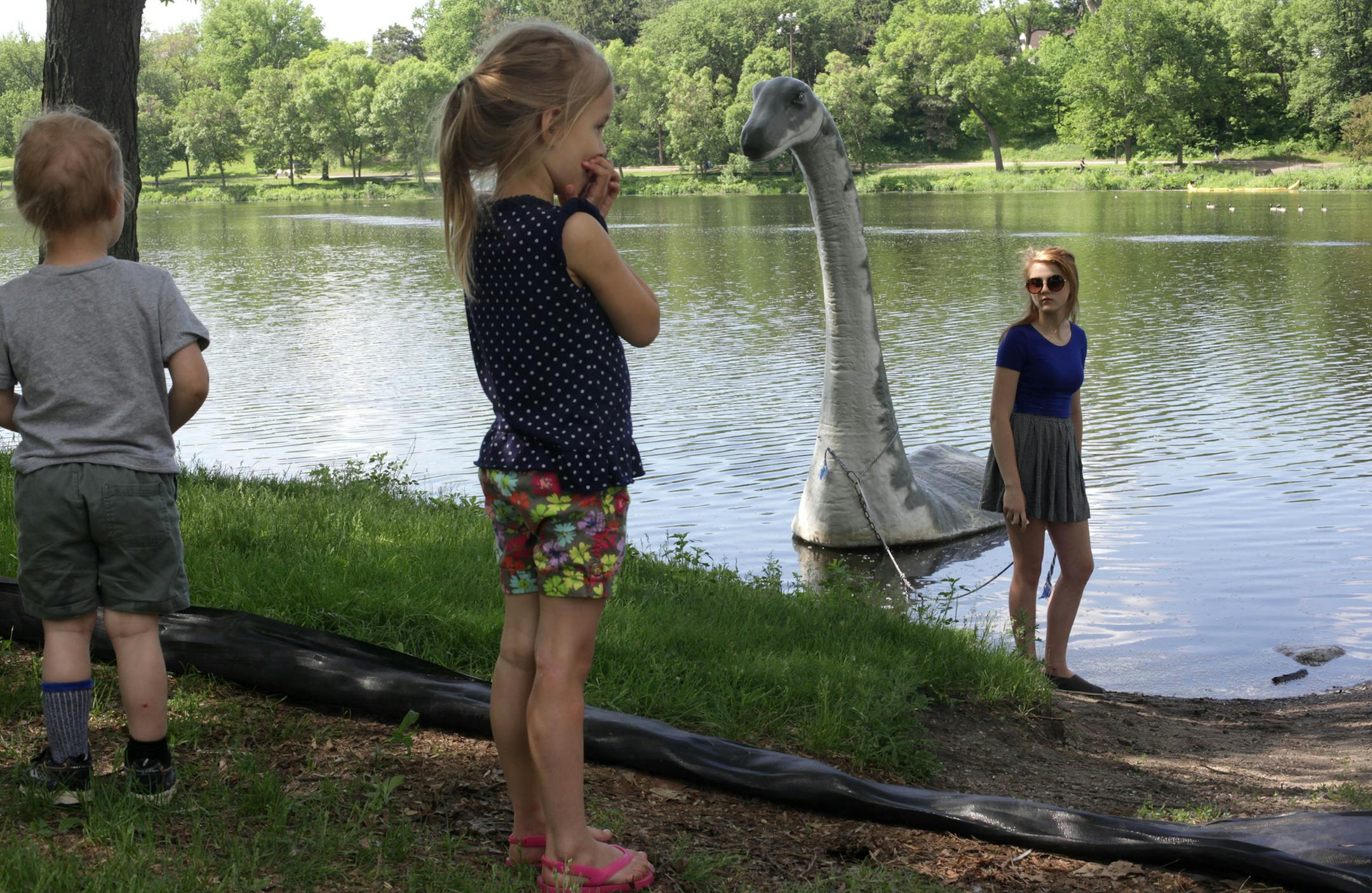 Sara Mageli, 15, holds on to a rope connected to Minne, a floating fiberglass sculpture, during the launch in Powderhorn Lake, while neighborhood children watch, on Wednesday morning. Minne will remain in Powderhorn Park through September.