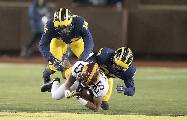 Minnesota's wide receiver Phillip Howard was plowed down by Michigan's defensive back Josh Metellus, left, and defensive back Tyree Kinnel, right, dur