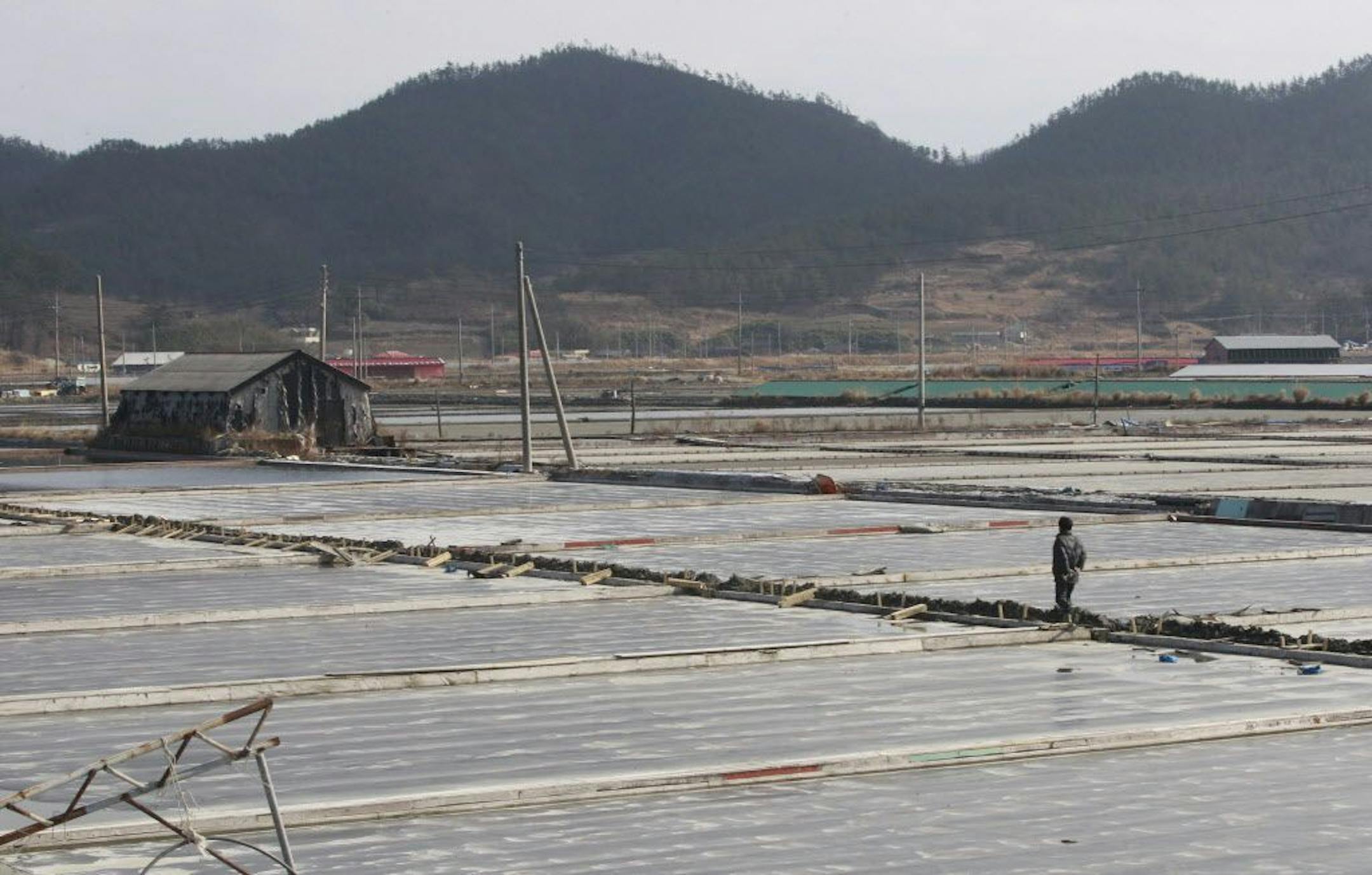 In this Feb. 19, 2014, a salt farm owner walks around his salt farm on Sinui Island, South Korea.