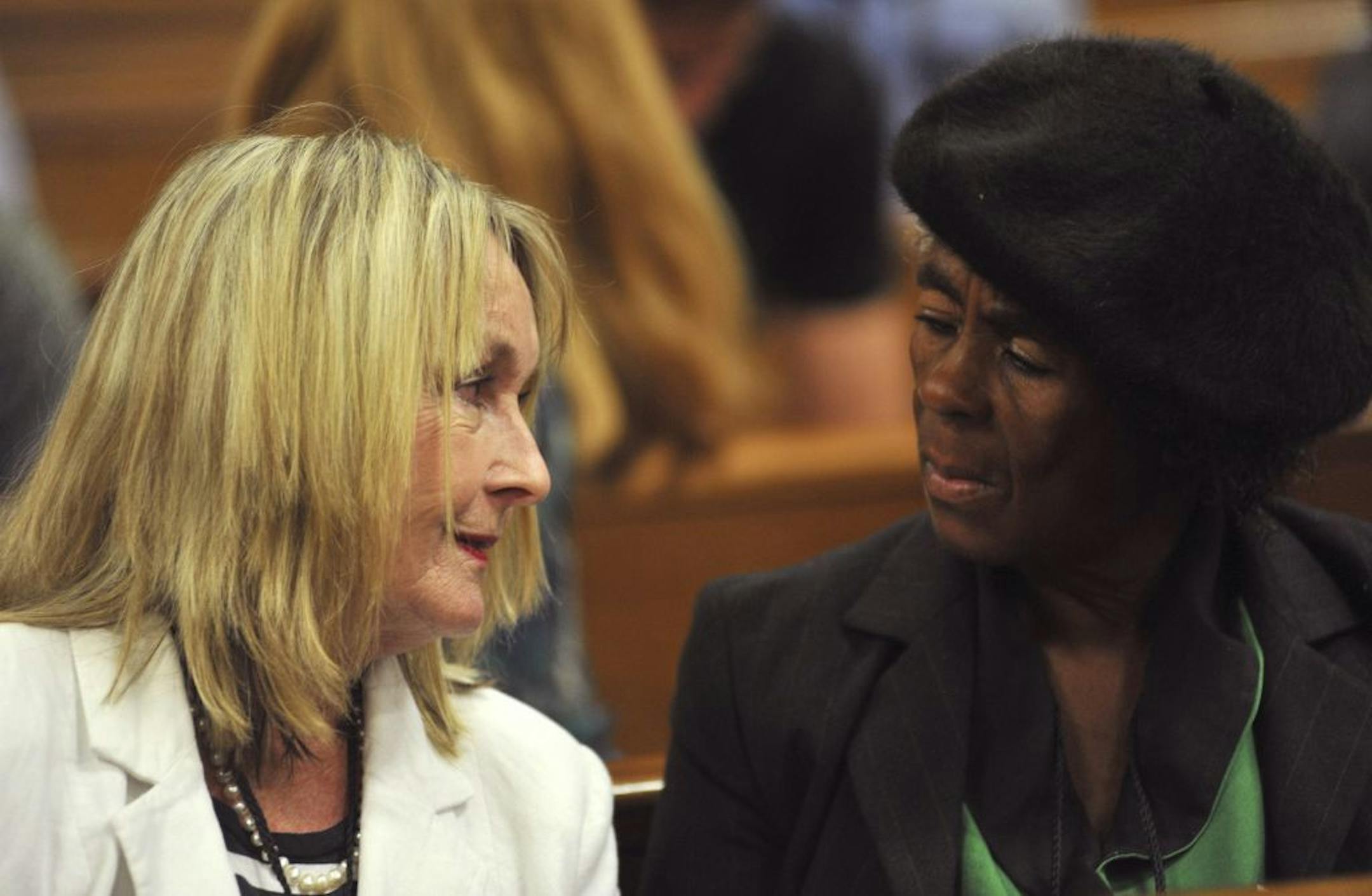 June Steenkamp, left, the mother of the late Reeva Steenkamp, talks with an unidentified member of the African National Congress Women's League as they wait for proceedings to get under way Monday, March 24, 2014, at the high court in Pretroia, South Africa.