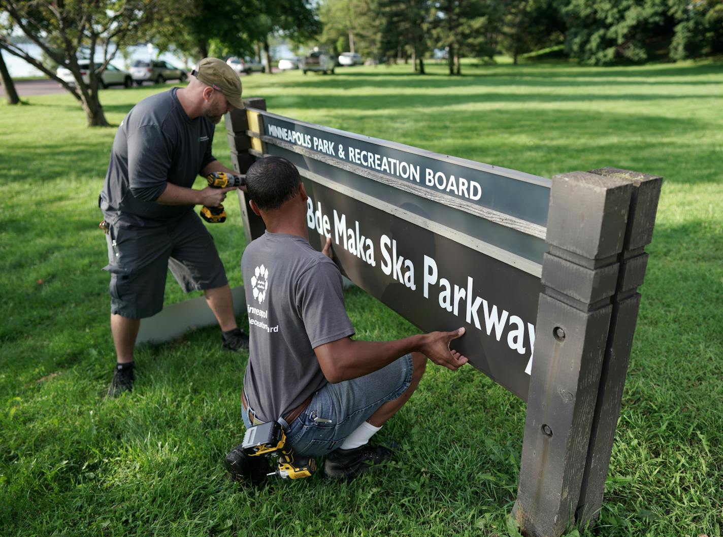 Minneapolis Park and Recreation Board (MPRB) workers install new placards changing East and West Lake Calhoun Parkways to East and West Bde Maka Ska Parkways.