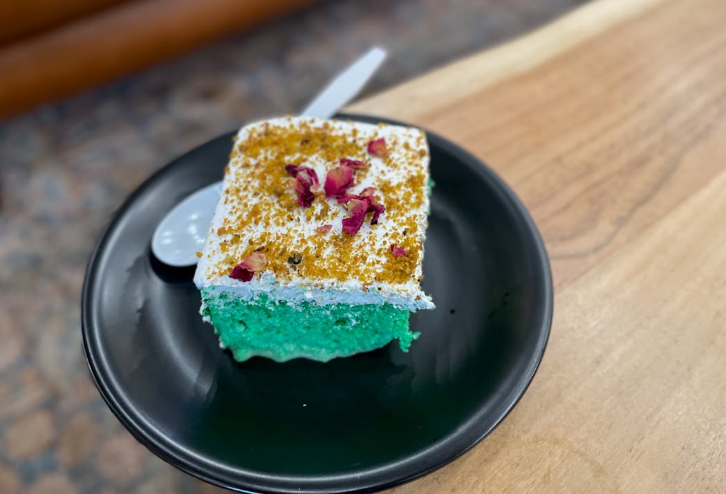 Qamaria's pistachio cake comes with a vibrantly green interior and a garnish of rose petals.