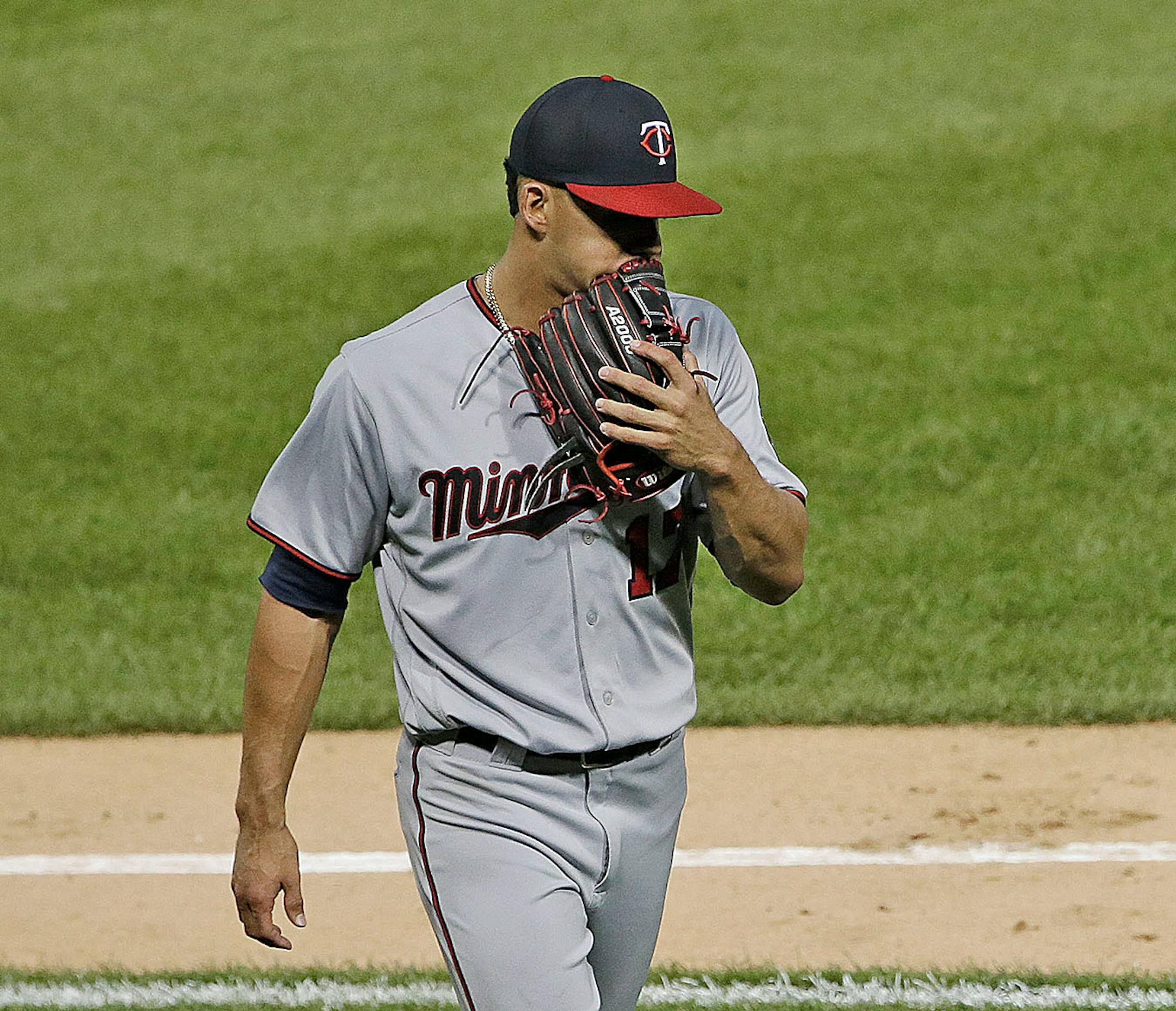 Minnesota Twins starting pitcher Jose Berrios covers his face with his glove as he walks back to the dugout after the second inning of a baseball game against the Chicago White Sox, Thursday, Aug. 24, 2017, in Chicago.