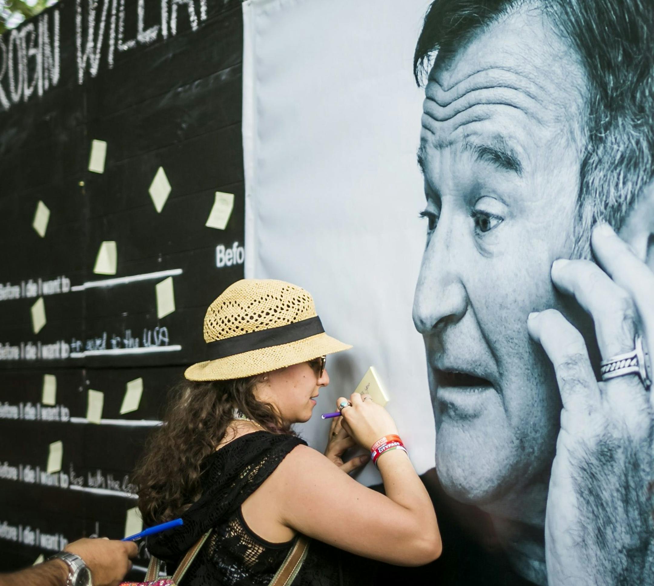 CAPTION CORRECTS DATE - Festival goers pay tribute to the late actor Robin Williams, who died Monday, Aug. 11, at a makeshift memorial at the 22nd Sziget (Island) Festival on the Shipyard Island in Northern Budapest, Hungary, Wednesday, Aug. 13, 2014. (AP Photo/MTI, Janos Marjai)