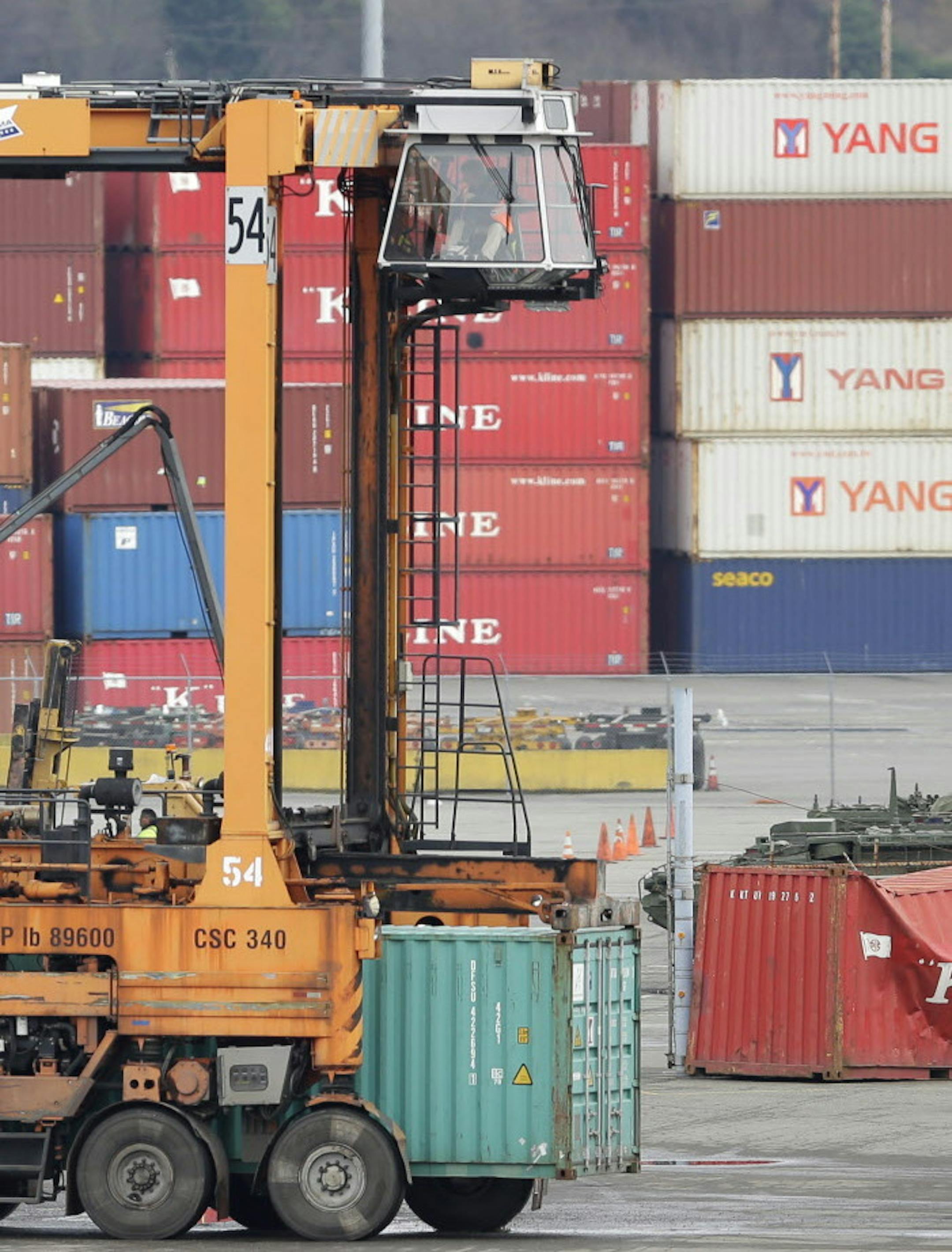 A driver sits high in the cab of a cargo container mover at the Port of Tacoma, Friday, Feb. 20, 2015, in Tacoma, Wash. With a Friday deadline looming, negotiators for the two sides in the contract dispute that has snarled international trade at U.S. West Coast seaports are laboring to reach a settlement as billions of dollars of cargo are sitting massive ocean-going ships anchored outside port facilities. (AP Photo/Ted S. Warren)