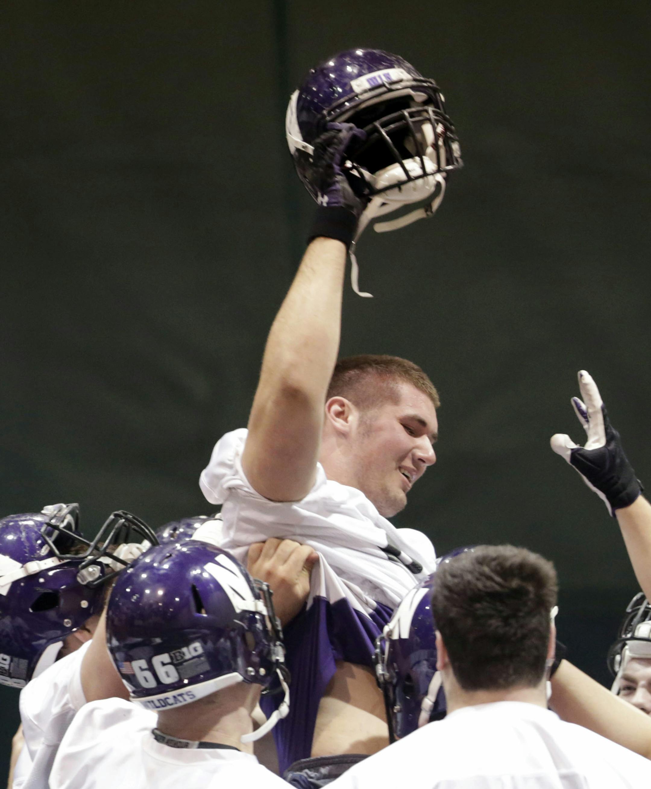 Northwestern's football team participates in an NCAA college spring football practice Tuesday, April 1, 2014, in Evanston, Ill. After spring break, Northwestern resumed spring football practices with a huge issue that could change the college sports landscape hanging over their heads. A regional director of the National Labor Relations Board ruled last week that the team can bargain with the school as employees. (AP Photo/M. Spencer Green)