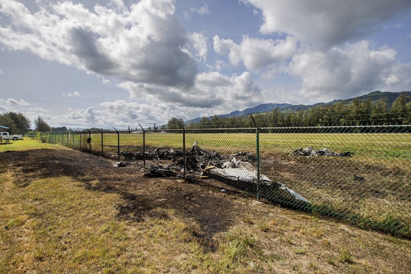 This is the site where a Beechcraft King Air twin-engine plane crashed Friday evening killing multiple people seen on Saturday, June 22, 2019, in Mokuleia, Hawaii. No one aboard survived the skydiving plane crash, which left a small pile of smoky wreckage near the chain link fence surrounding Dillingham Airfield, a one-runway seaside airfield.