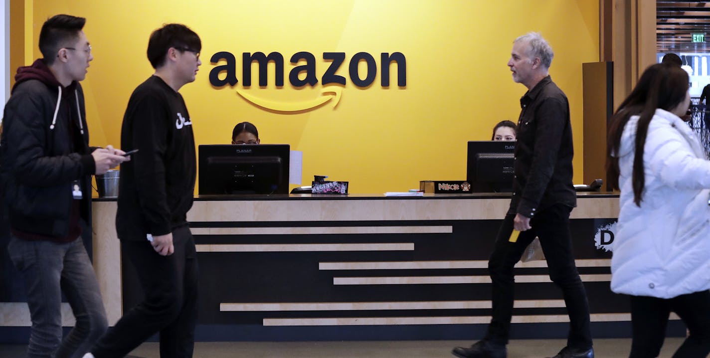 Employees walk through a lobby at Amazon's headquarters Tuesday, Nov. 13, 2018, in Seattle. Amazon, which is growing too big for its Seattle hometown, is spreading out to the East Coast. The online shopping giant ended its 14-month-long competition for a second headquarters Tuesday by selecting New York and Arlington, Va., as the joint winners. (AP Photo/Elaine Thompson) ORG XMIT: WAET102