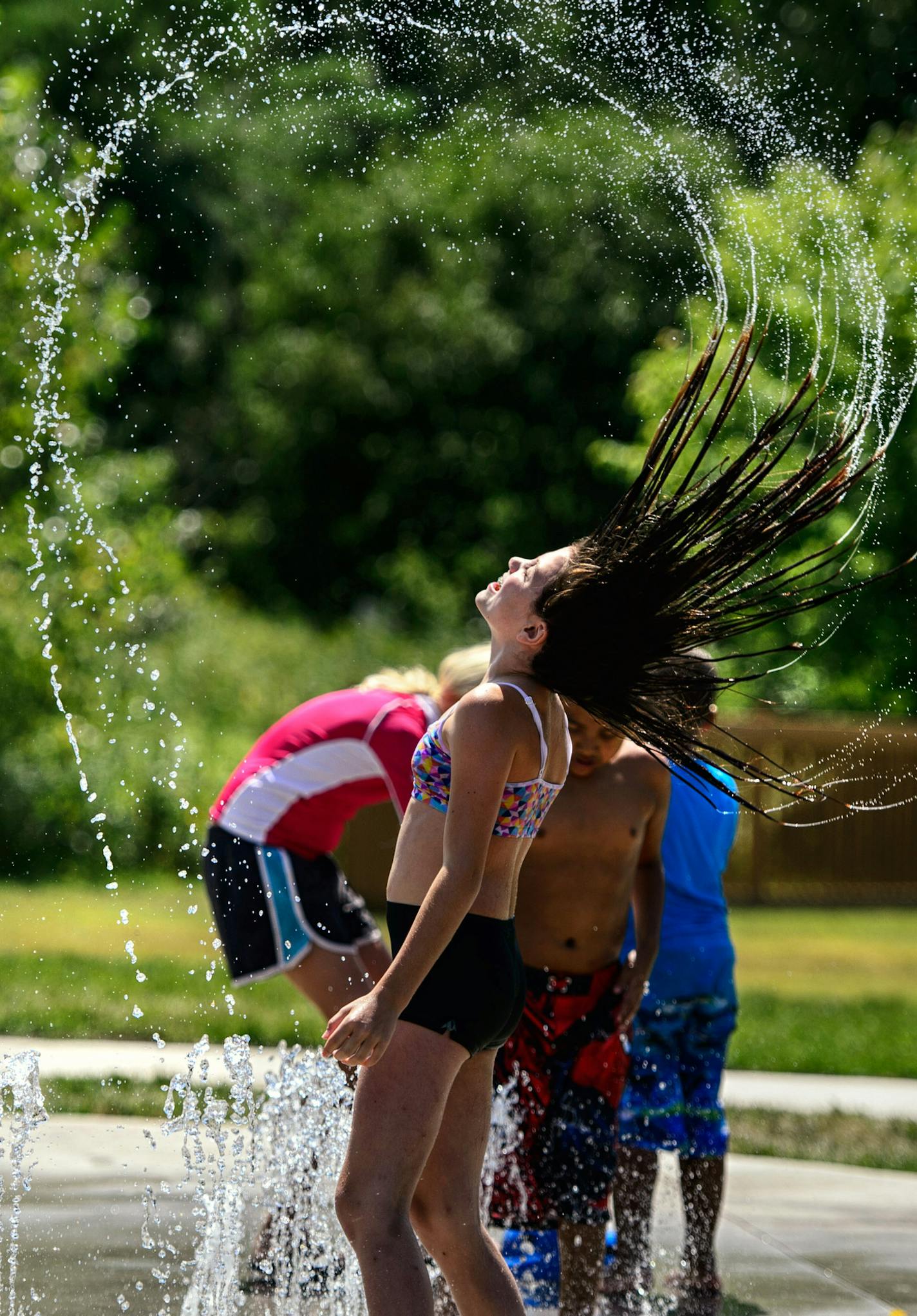 Hannah Jonus, 11, of Burnsville whiped her hair through fountains at Cliff Fen Park. Kids play in the new splash pad at Cliff Fen Park in Burnsville, MN. Water from the park is not reused but drains into the nearby fen. Water flows rotate through only a few of the pad's features an any time and the system automatically shuts off every few minutes requiring a user to step on a foot switch to restart it. ] GLEN STUBBE * gstubbe@startribune.com Tuesday, August 4, 2015 Kids play in the new splash pa