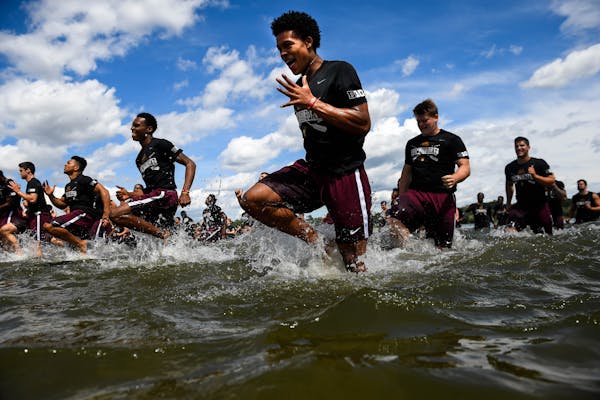 Gophers wide receiver Demetrius Douglas, center, and fellow teammates ran in shallows of Lake Nokomis during practice Friday afternoon. ] AARON LAVINS