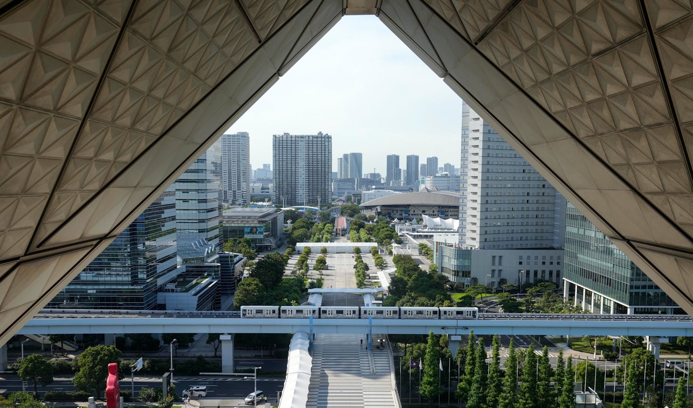 A train passes the entrance of the Main Press Center of the 2020 Summer Olympics, Tuesday, July 20, 2021, in Tokyo.