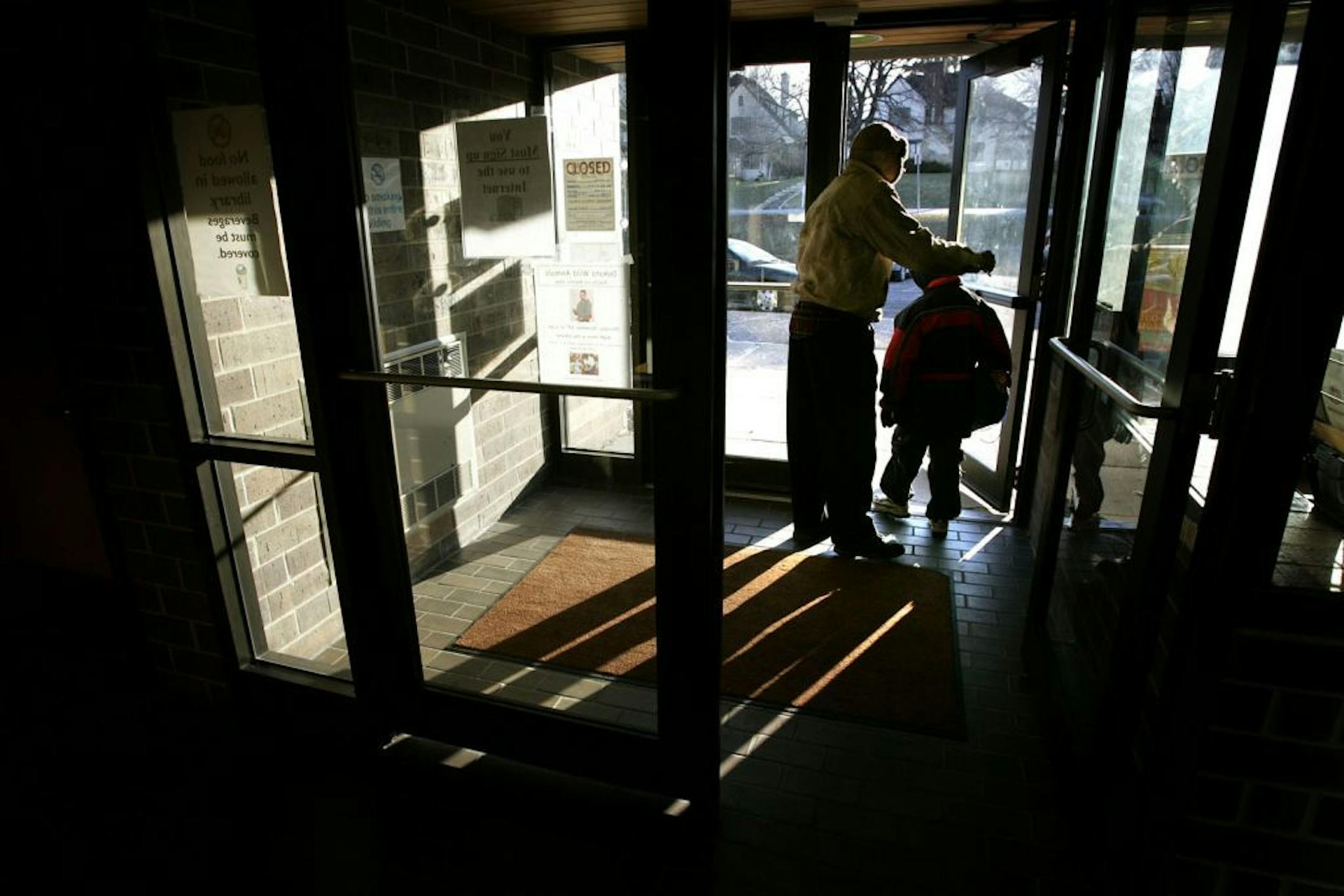 ELIZABETH FLORES � eflores@startribune.com Minneapolis, MN- December 6, 2006 - Louis Burks helps his son Elijah Vanderpoel, 8, cq, leave the Webber Park Library before it closes on Wednesday. Burks said he and his son visit the library at least once a week.