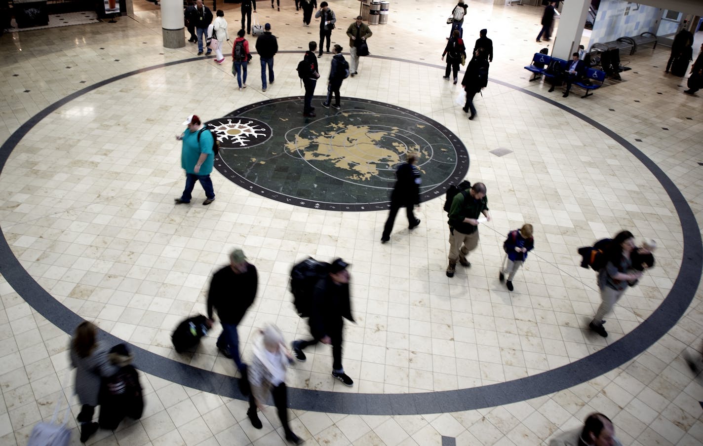 Travelers at Minneapolis-St. Paul International Airport walked past "You Are Here," a floor mosaic by Andrea Myklebust and Stanton G. Sears.