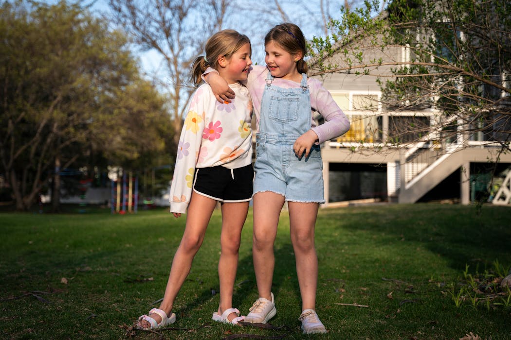 Twins Ellie and Addie Getman stand arm-in-arm together in their backyard in April. Their mother Meta, a fertility coach who gave birth to the twins through IVF, is joining other advocates in calling for legislators to protect the procedure in Minnesota.
