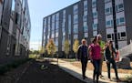 The project team walked through a courtyard that separates the Green Communities building, left, from the more energy-efficient Passive House building