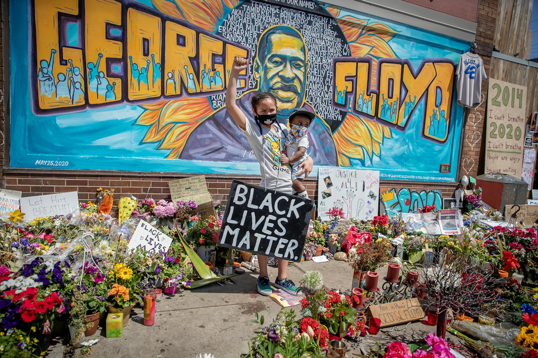 Samaya Bunbuenano, 12, held her little brother Dayton Majors, 11, in front of a large mural of George Floyd on Wednesday at Cup Foods in Minneapolis.