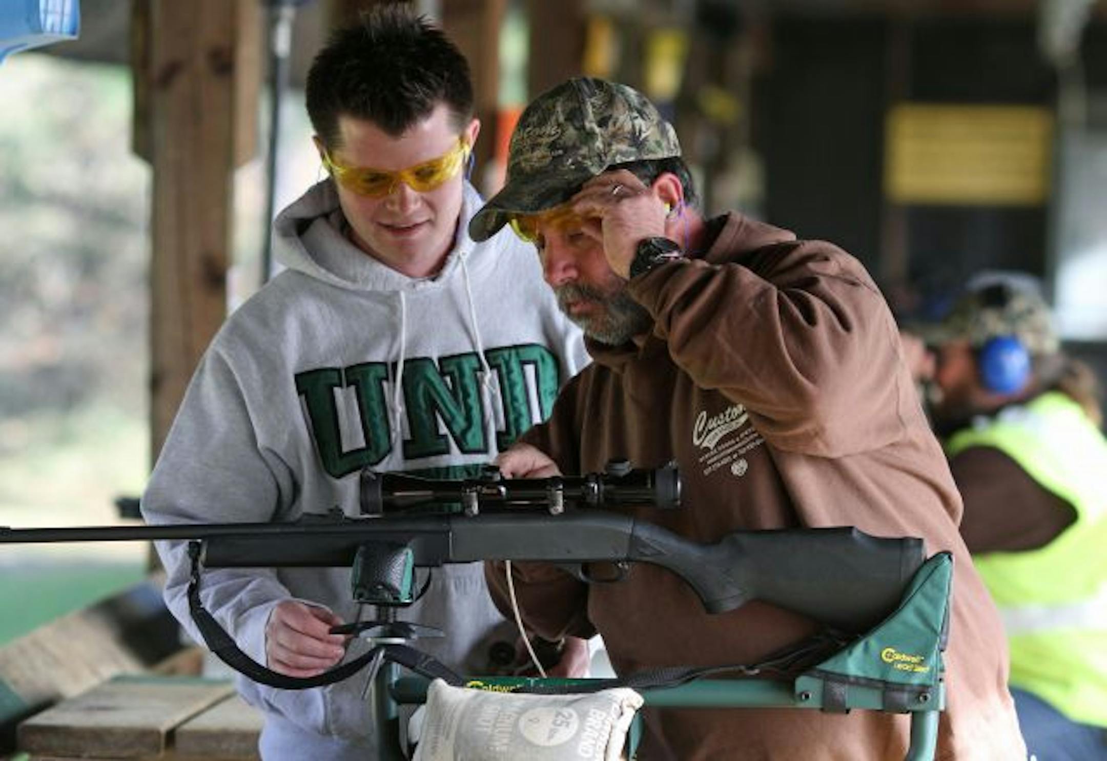 (left to right) Chris Ahrens helped his dad, Gary Ahrens, (both from Eagan) sight in his rifle while shooting at the Oakdale Gun Club. They were shooting on the 100 yard range.