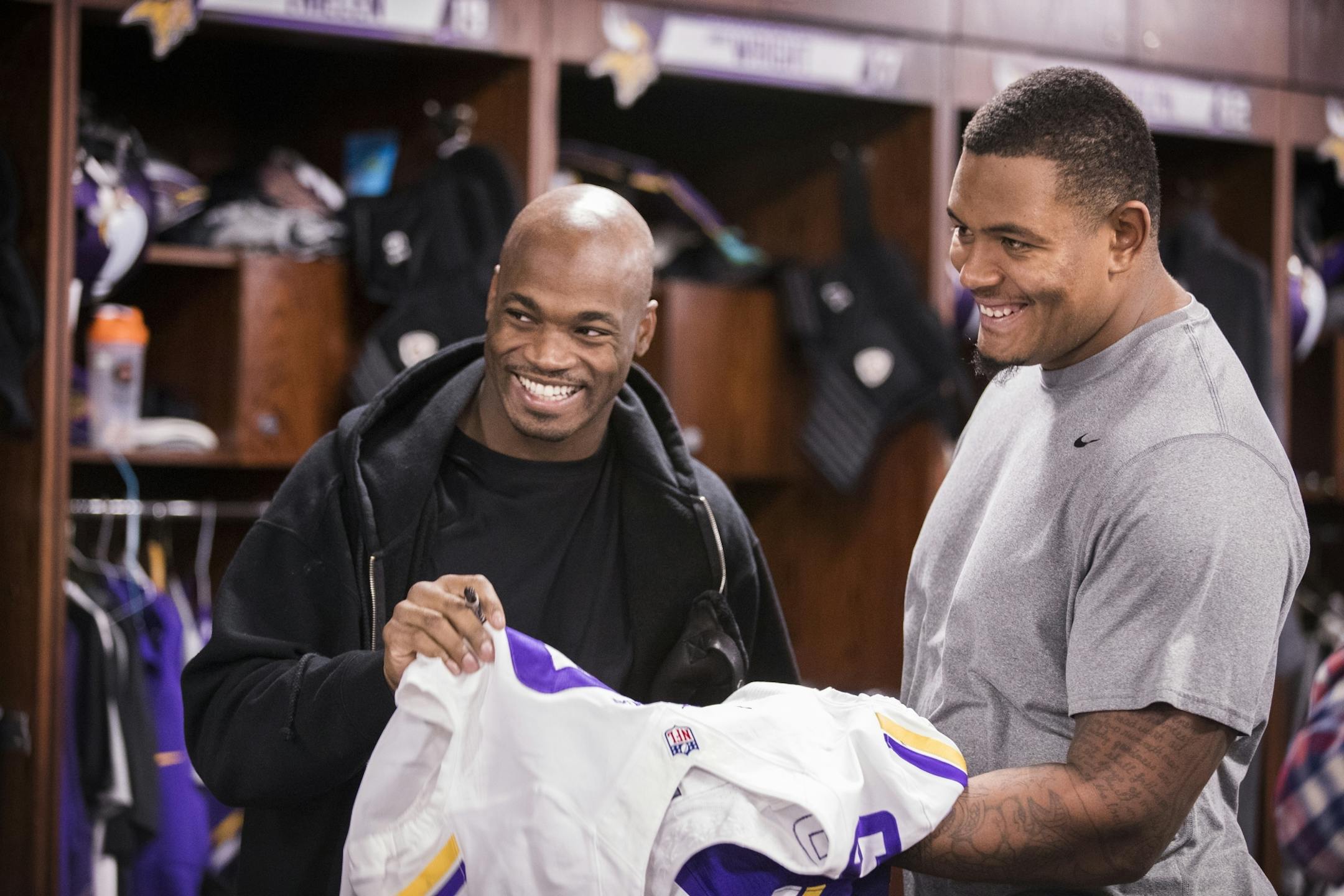 Adrian Peterson, left, signs a jersey for teammate Rashod Hill.