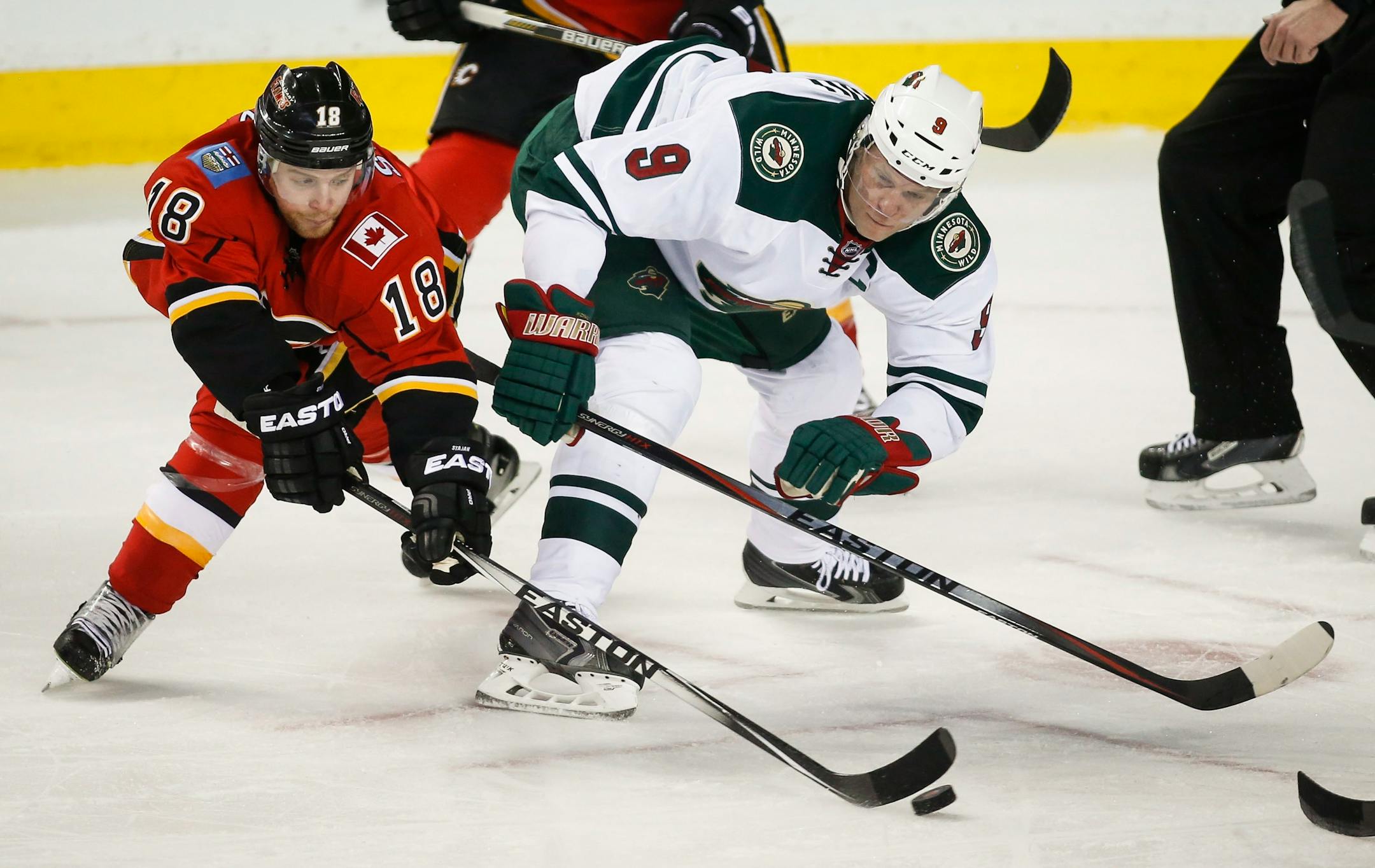 Minnesota Wild Mikko Koivu, from Finland,, right, battles Calgary Flames Matt Stajan for the puck during the first period of an NHL hockey game, Wednesday, Feb. 18, 2015 in Calgary, Alberta. (AP Photo/Canadian Press, Jeff McIntosh)