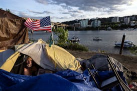Frank, a homeless man sits in his tent with a river view in Portland, Ore., June 5, 2021.