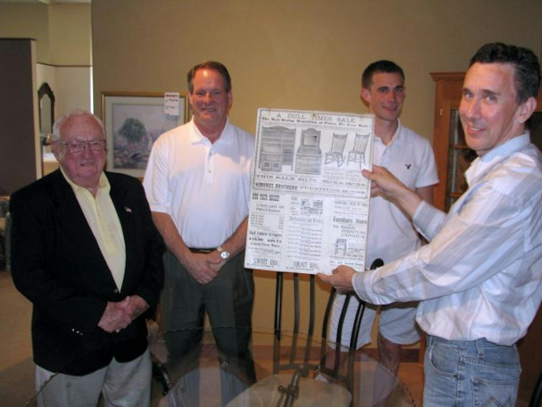 Jim O�Brien (left), ran Simonet�s Furniture until it closed in 2009. His son, Mike O�Brien (second from left), reopened the store with Mike Kranz (far right) in July. Keeping with the tradition of families in the store, Kranz�s son, Mike Kranz, Jr. (third from left) also works in the furniture store now. Mike Kranz is holding an ad from the original Simonet�s Furniture. The photo was taken inside the store.