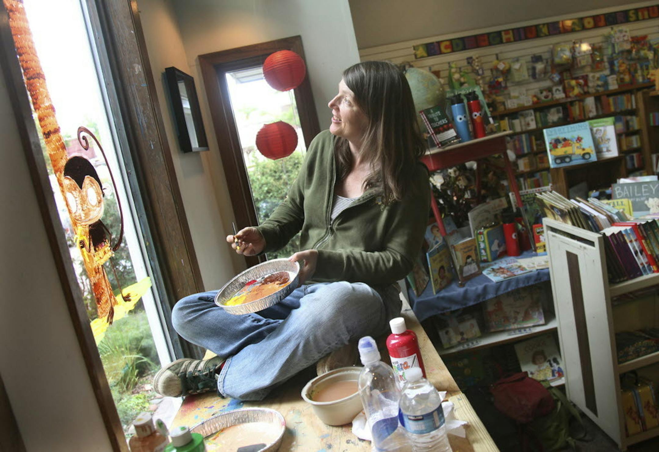 Chris Monroe paints Chico Bon Bon on the window of the Red Balloon bookstore in St. Paul.