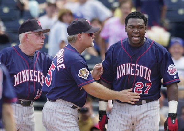 Minnesota Twins' David Ortiz, right, is moved toward the dugout by manager Tom Kelly, left, and third base coach Ron Gardenhire, center, after being e