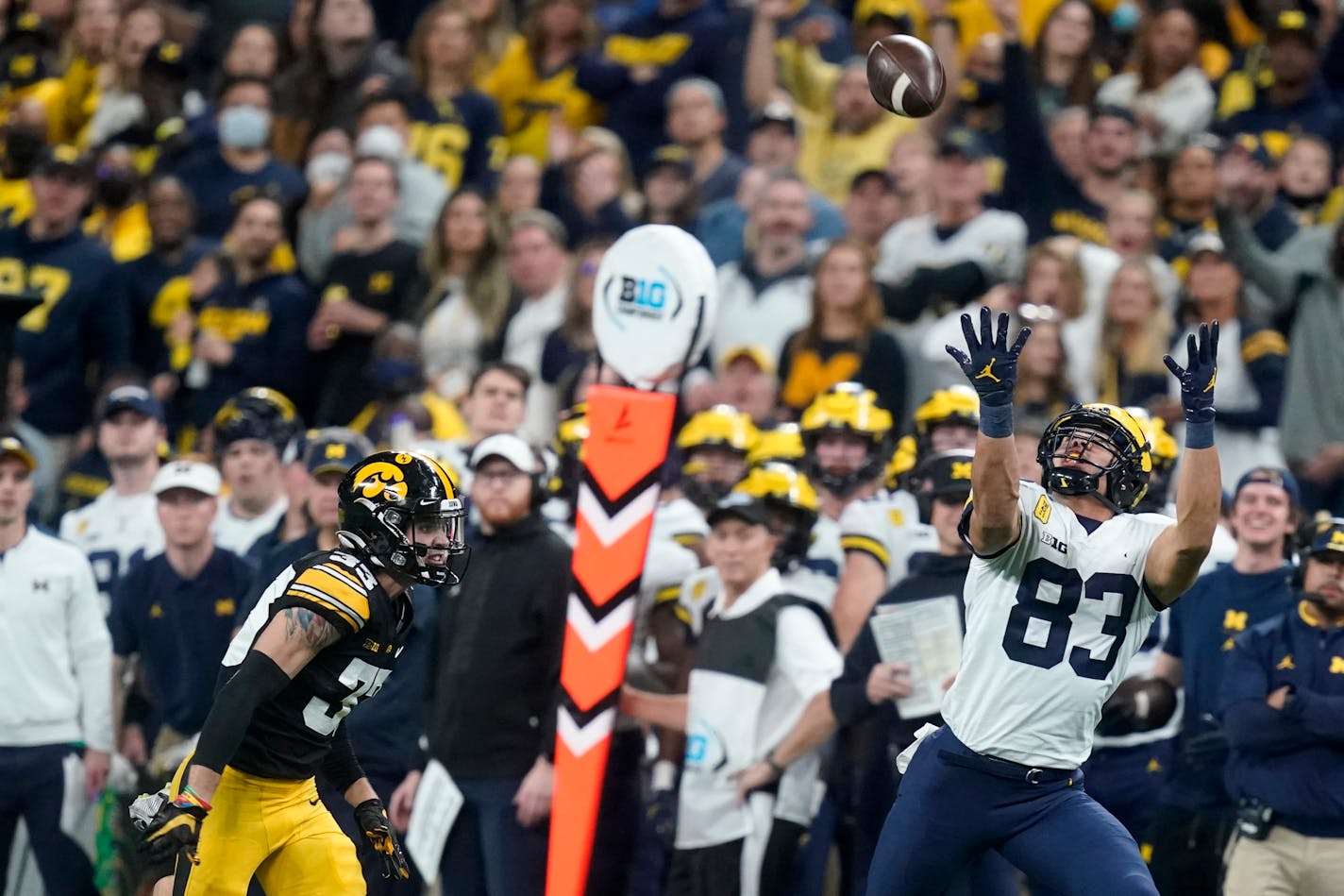 Michigan tight end Erick All (83) catches a pass ahead of Iowa defensive back Riley Moss (33) during the second half of the Big Ten championship NCAA college football game, Saturday, Dec. 4, 2021, in Indianapolis. (AP Photo/Darron Cummings)