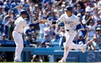 Dodgers star Shohei Ohtani celebrates with third base coach Dino Ebel, left, after hitting a home run during the eighth inning against the Braves on S