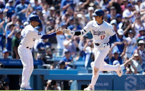 Los Angeles Dodgers designated hitter Shohei Ohtani celebrates with third base coach Dino Ebel, left, after hitting a home run during the eighth innin