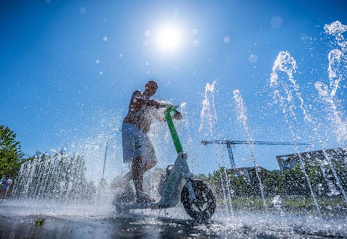 Tomas from Berlin rides his e-scooter through the water fontaine in front of the Chancellery in Berlin, Germany, Wednesday, July2, 2025.