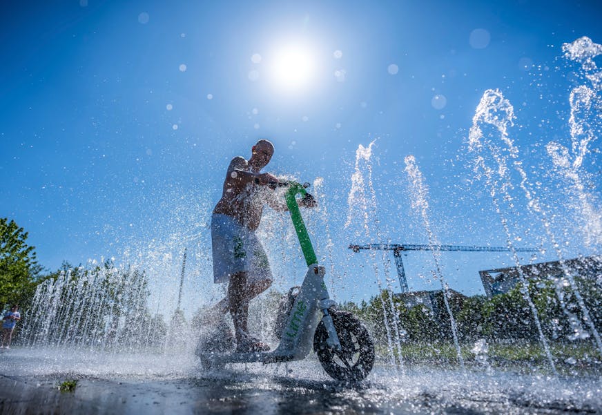 Tomas from Berlin rides his e-scooter through the water fontaine in front of the Chancellery in Berlin, Germany, Wednesday, July2, 2025.