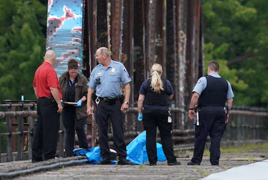 A man's body was covered with a blue tarp as police investigated the scene where he was found dead on Aug. 13, 2019 on the railway tracks near the intersection of 16th Avenue and NE Marshall Street.