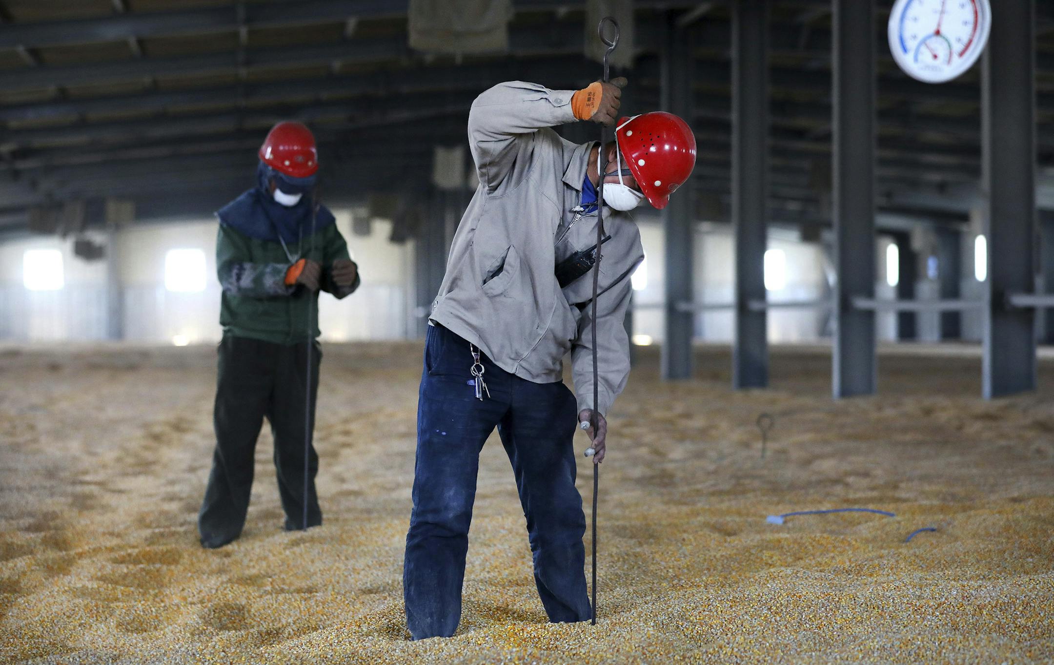 In this April 13, 2020, photo released by China's Xinhua News Agency, workers wear facemasks as they check the temperature of a granary in Anshan in northeastern China's Liaoning Province. China has reported its biggest economic decline since the 1970s as it fought the coronavirus in the first quarter of the year. (Yao Jianfeng/Xinhua via AP) ORG XMIT: XIN802