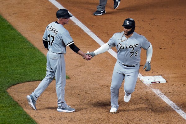 Chicago White Sox’s Yermin Mercedes, right, is congratulated by third base coach Joe McEwing after his home run off Minnesota Twins’ Willians Astu