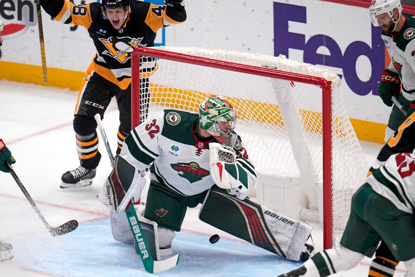 A shot by Pittsburgh Penguins' Reilly Smith, not shown, get past Minnesota Wild goaltender Filip Gustavsson (32) as Penguins' Valtteri Puustinen, top left, begins to celebrate during the first period of an NHL hockey game in Pittsburgh, Monday, Dec. 18, 2023. (AP Photo/Gene J. Puskar)