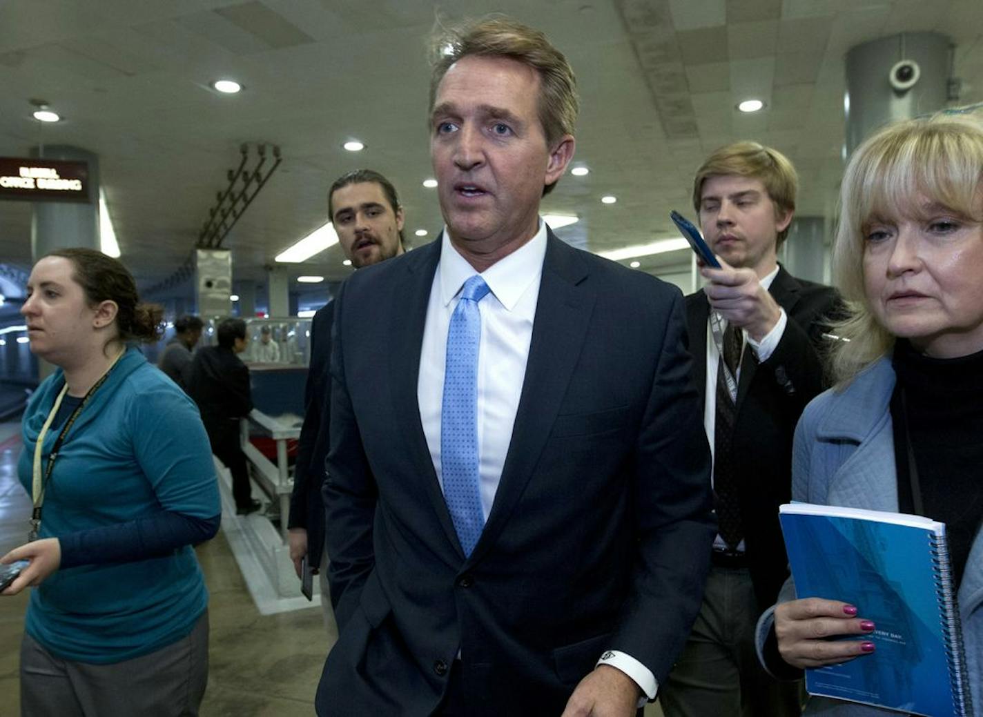 Sen. Jeff Flake, R-Ariz., a member of the Senate Foreign Relations Committee, speaks with reporters on his way to the senate chamber, as the Senate takes up a House-passed bill that would pay for President Donald Trump's border wall and avert a partial government shutdown, at the Capitol in Washington, Friday, Dec. 21, 2018.