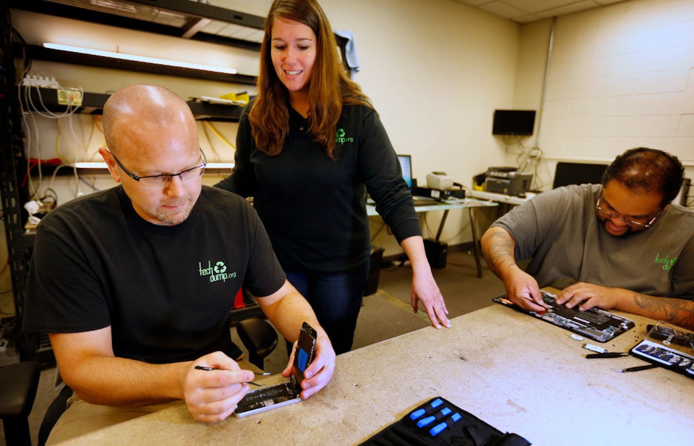 Tech Dump CEO Amanda LaGrange (center) chats with technicians Dan Saba (left) and Alonzo Nelson (right) in 2016 as they worked on refurbishing an iPhone and computer board. Star Tribune file photo.