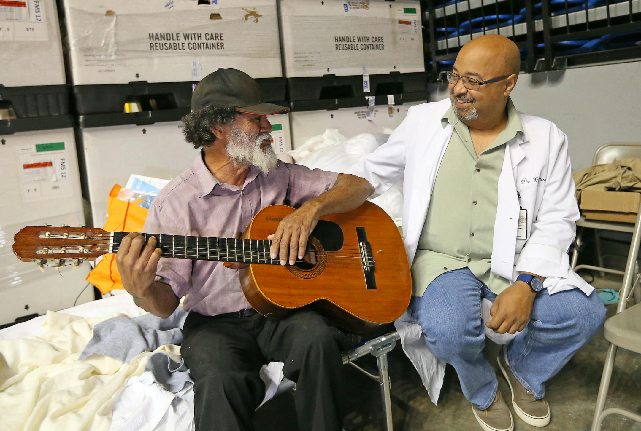 Santos Candelaria plays guitar and sings with Alfredo Guzman, MD VA Doctor from Oxford, Ala., and Natural de Villalba P.R., at the temporary hospital set up at the arena in the Acropolis Sports Complex in Manati during the aftermath of Hurricane Maria on October 27, 2017, in Puerto Rico. Candelaria sings to his sick wife, Evelyn Rivera Vargas, and to the staff. (David Santiago/El Nuevo Herald/TNS) ORG XMIT: 1215093