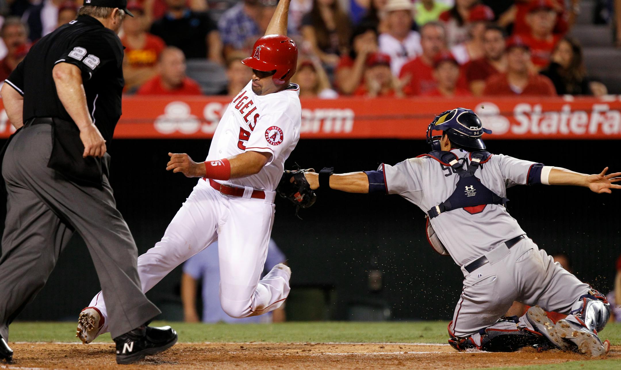 Los Angeles Angels designated hitter Albert Pujols (5) is safe at the plate as Minnesota Twins catcher Kurt Suzuki, right, doesn't hold onto the throw from center field on a single by David Freese during the sixth inning of a baseball game in Anaheim, Calif., Tuesday, July 21, 2015. Home plate umpire Joe West (22) looks on to make the call. (AP Photo/Alex Gallardo)