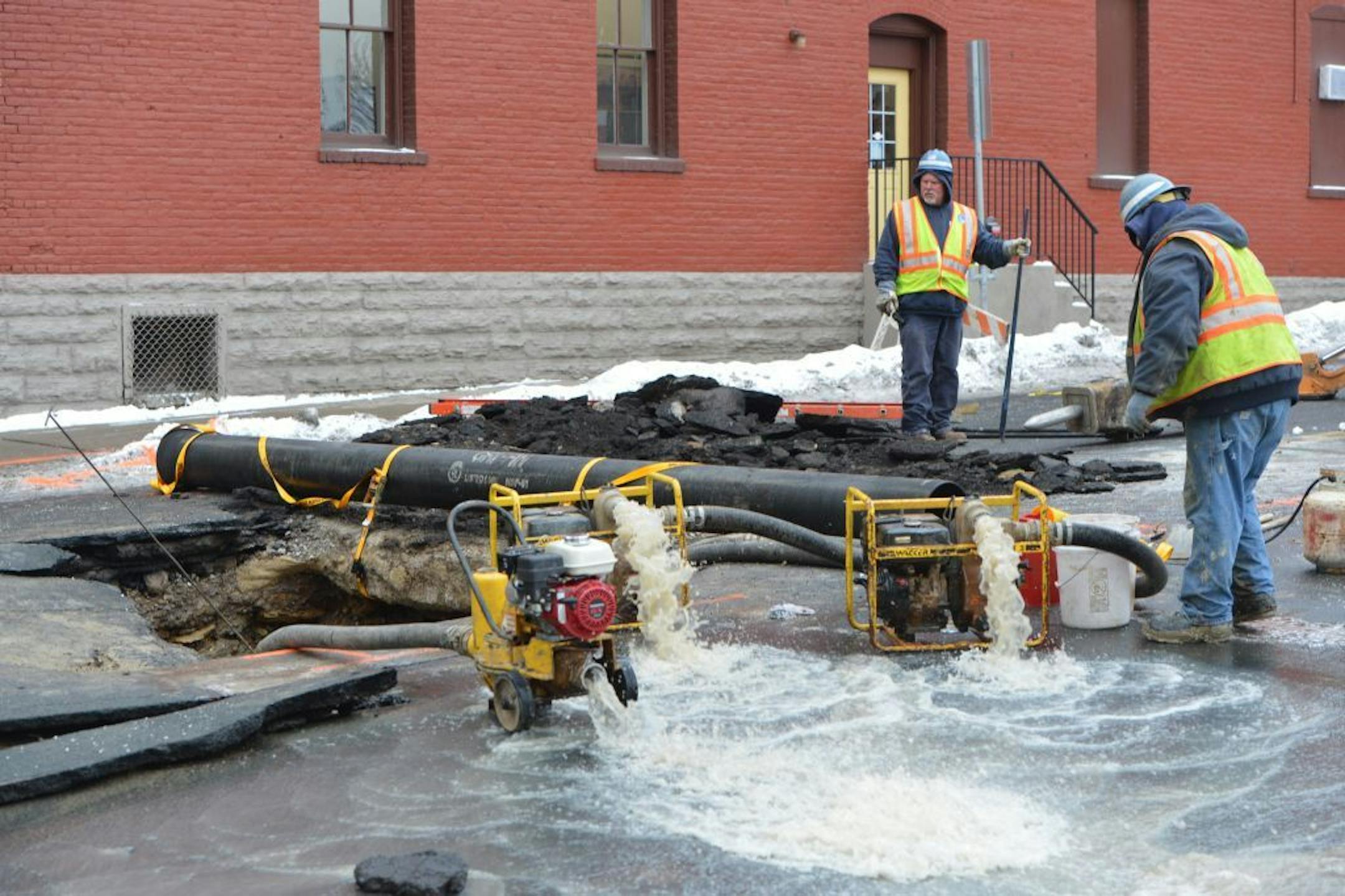 Workers pump out water from a hole where a water main ruptured in downtown St.Paul on Wall St. between 5th and 6th Streets, near the Farmer's Market.