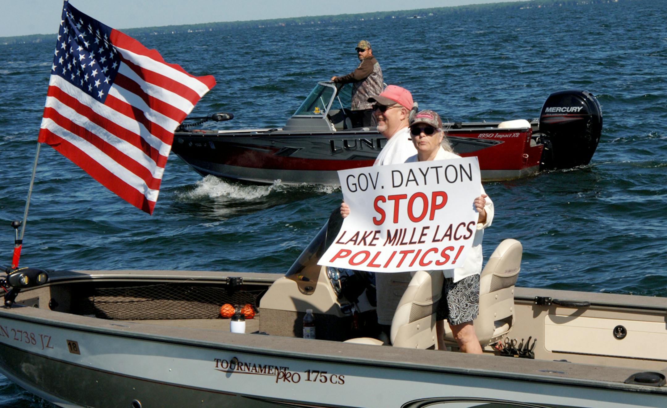 In this Saturday, July 8, 2017, photo provided by Mille Lacs Messenger, people on a boat encircle Minnesota Gov. Mark Dayton, not pictured, on Mille Lacs Lake to protest a temporary ban on walleye fishing in Minnesota. The Star Tribune reports that Dayton was with a group fishing for bass on the lake Saturday when dozens of protesters encircled him. (Vivian LaMoore/Mille Lacs Messenger via AP) ORG XMIT: MIN2017071018265132
