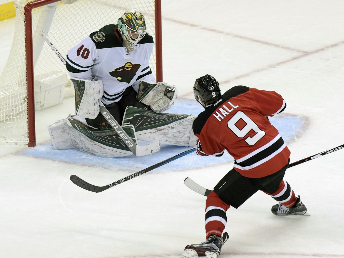 New Jersey Devils' Taylor Hall (9) puts the puck into the net for the winning goal past Minnesota Wild goaltender Devan Dubnyk during the overtime period of an NHL hockey game Saturday, Oct. 22, 2016, in Newark, N.J. (AP Photo/Bill Kostroun)