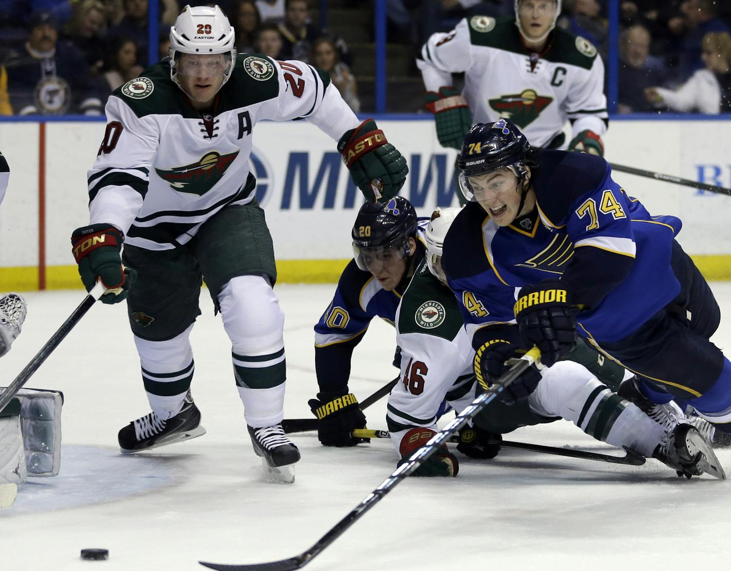 St. Louis Blues' T.J. Oshie (74) and Minnesota Wild's Ryan Suter (20) reach for a loose puck during the second period of an NHL hockey game Thursday, March 27, 2014, in St. Louis. (AP Photo/Jeff Roberson