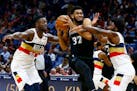 Minnesota Timberwolves center Karl-Anthony Towns (32) drives to the basket as New Orleans Pelicans forwards Julius Randle (30) and Solomon Hill (44) d