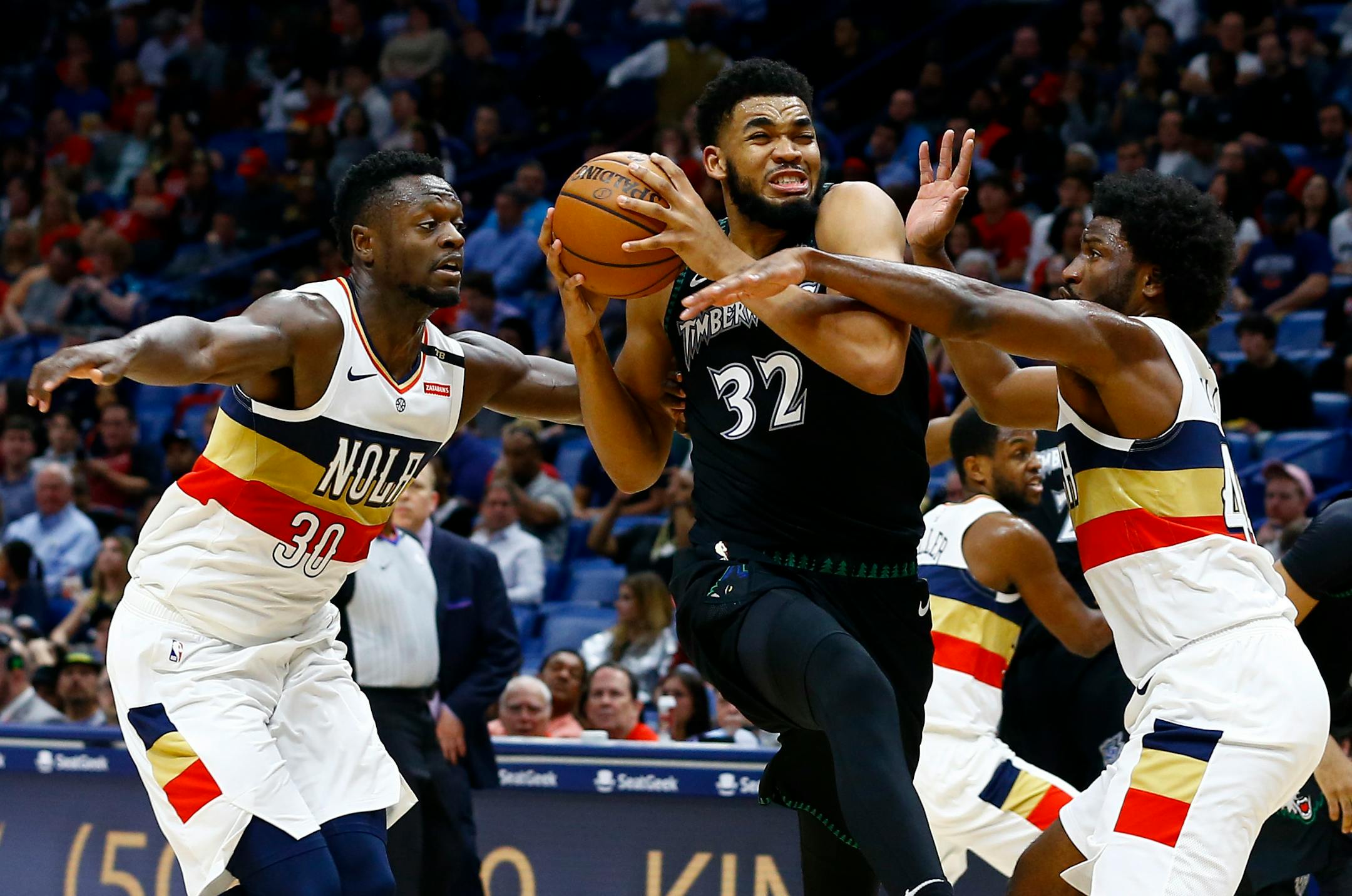 Minnesota Timberwolves center Karl-Anthony Towns (32) drives to the basket as New Orleans Pelicans forwards Julius Randle (30) and Solomon Hill (44) defend during the first half of an NBA basketball game, Monday, Dec. 31, 2018, in New Orleans. (AP Photo/Butch Dill)