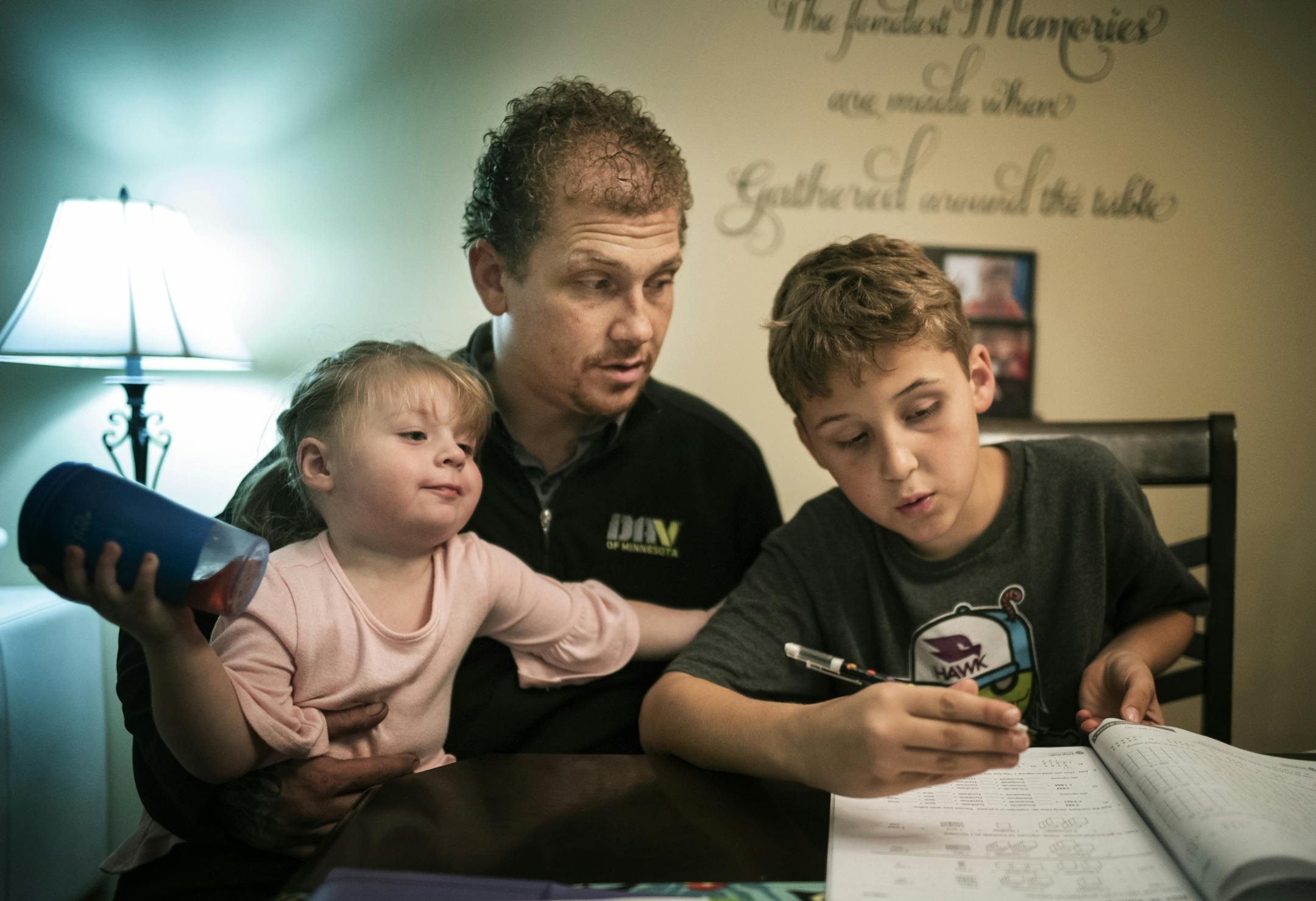 Alex Kempe helps his oldest son Aiden,9, with his math homework while youngest Sabriella,2, gets in on the action.